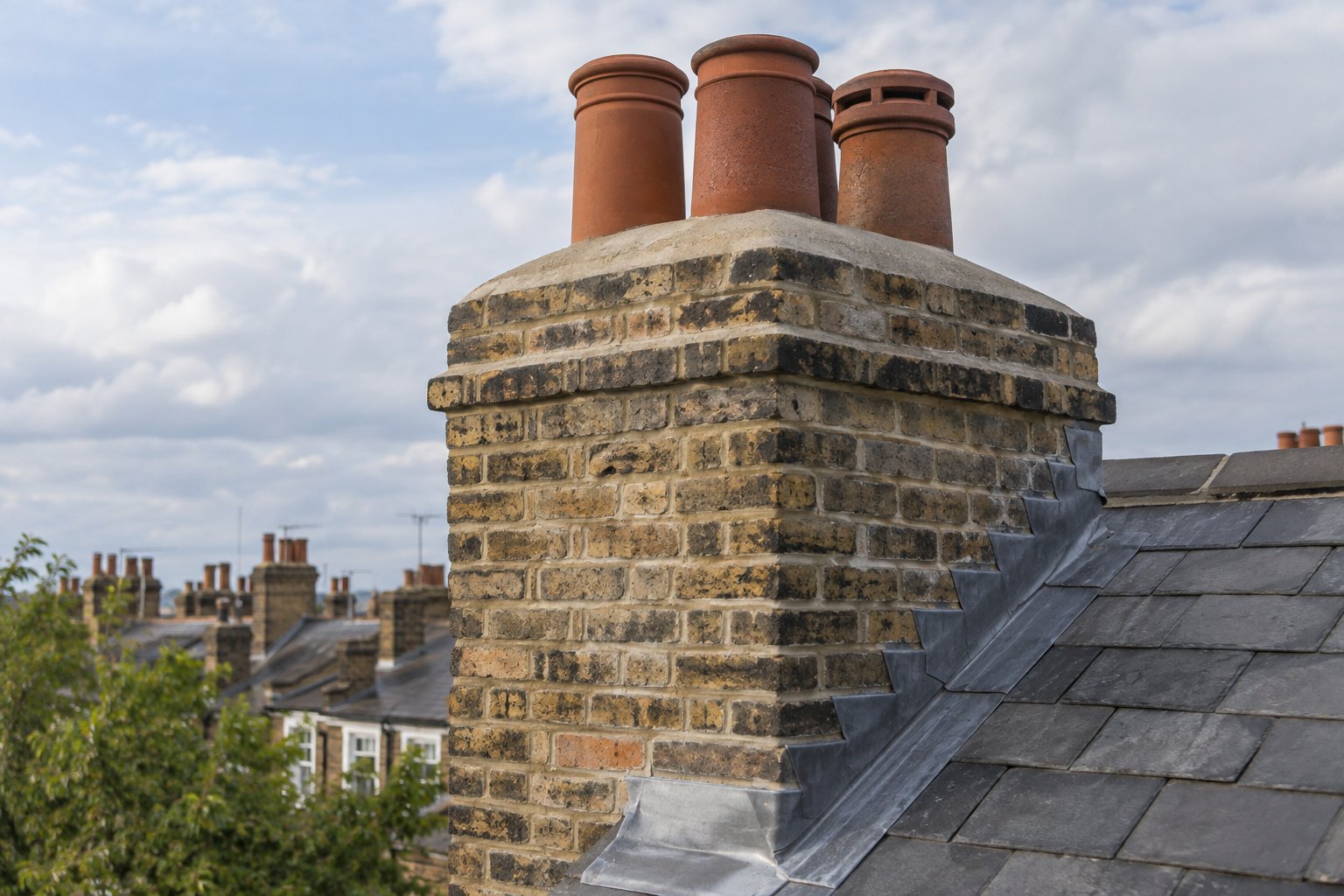 Repointed brick chimney with terracotta pots and stepped lead flashing